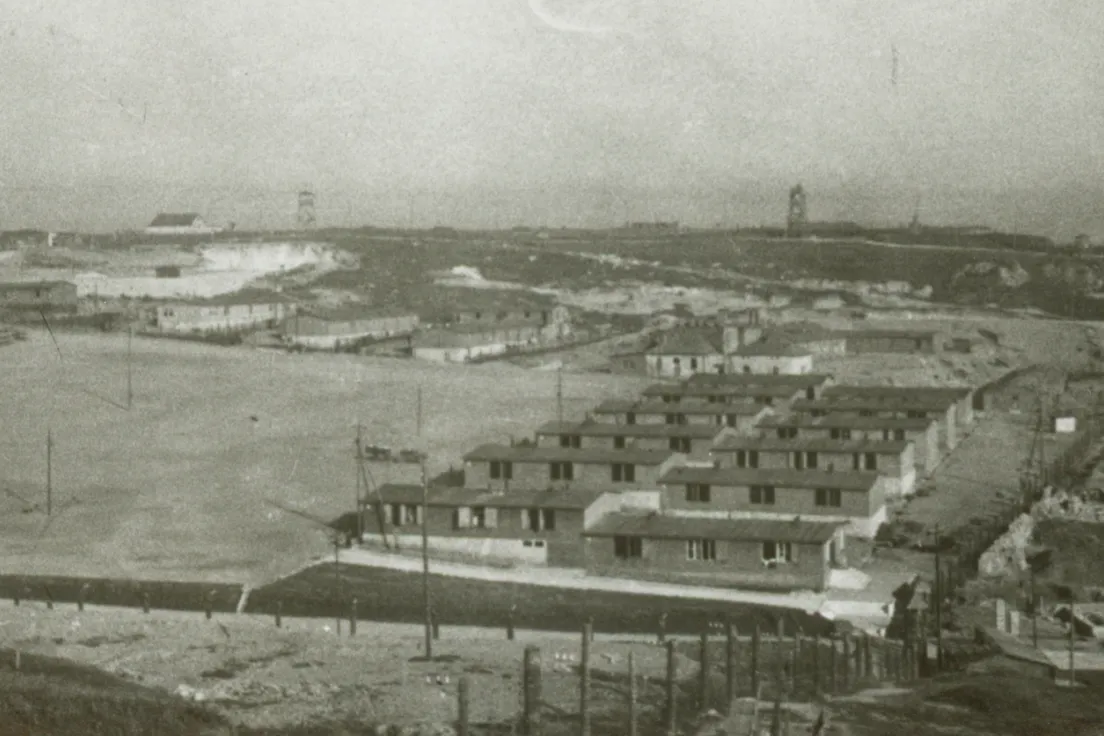 Na zdjęciu po prawej stronie placu apelowego widoczne są baraki dla polskich więźniów. (Fot. 1944 r., obiekty na planie obozowym oznaczono numerami 52-57)